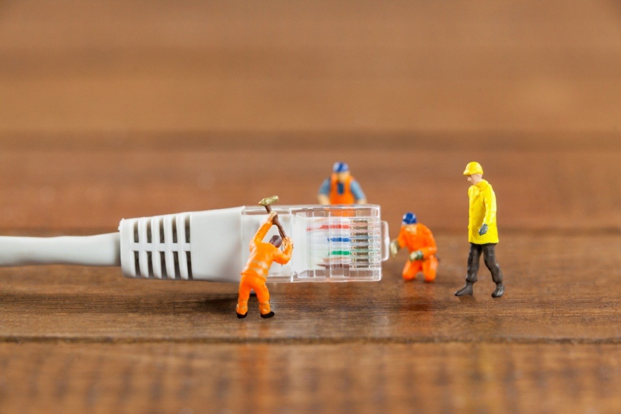 Miniature engineer and workers working with lan cable on wooden table