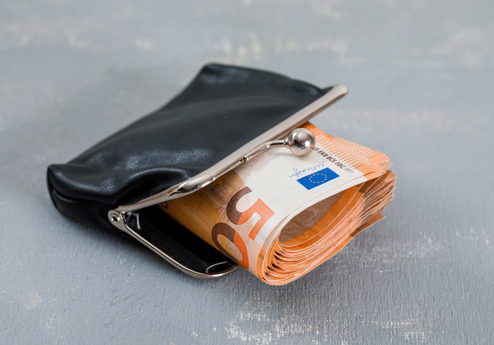 Monetary concept with banknotes in purse on plaster background high angle view.