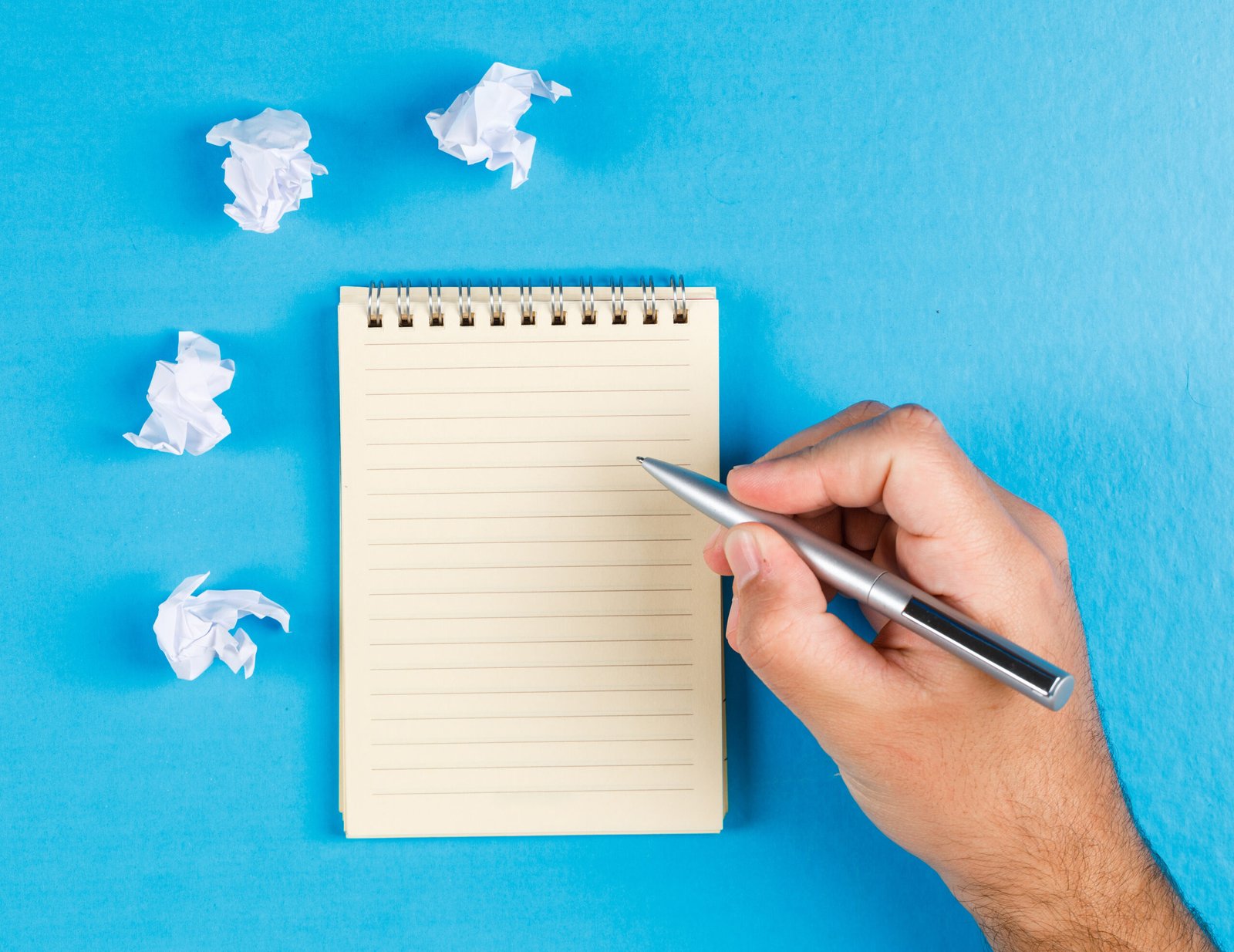 Business concept with crumpled paper wads on blue background flat lay. businessman taking notes on paper.